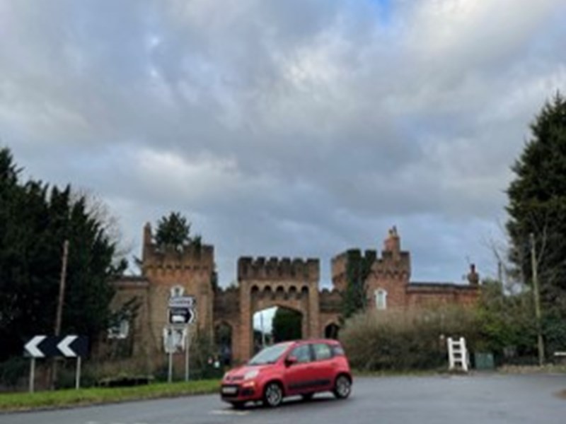 car on road in front of gateway with castellations