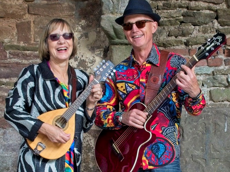 Image of the muscians called Jane and Nick standing and smiling with their stringed instruments
