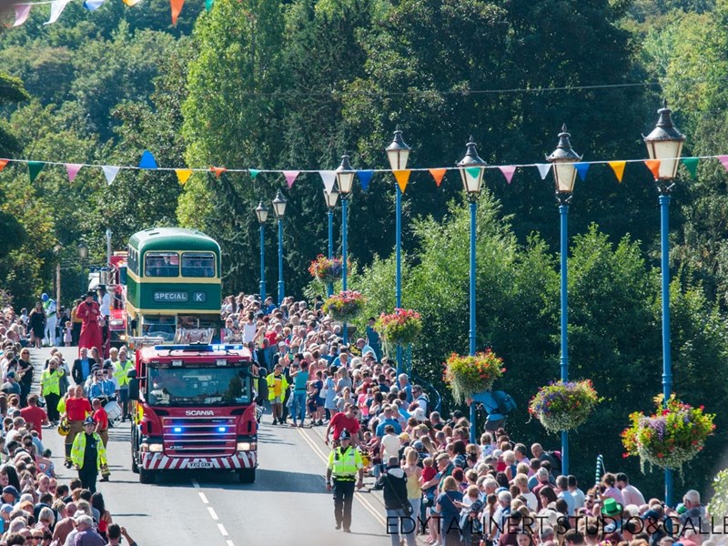 Fire engine and double-decker bus in a carnival parade driving over the bridge in Stourport on Severn with crowds of people stood watching