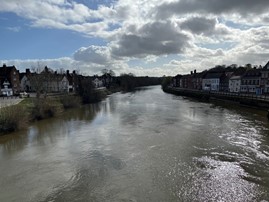 wide swirling river with buildings visible on the banks
