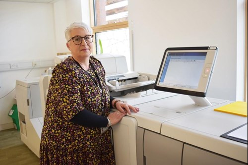 woman standing at large printer and screen