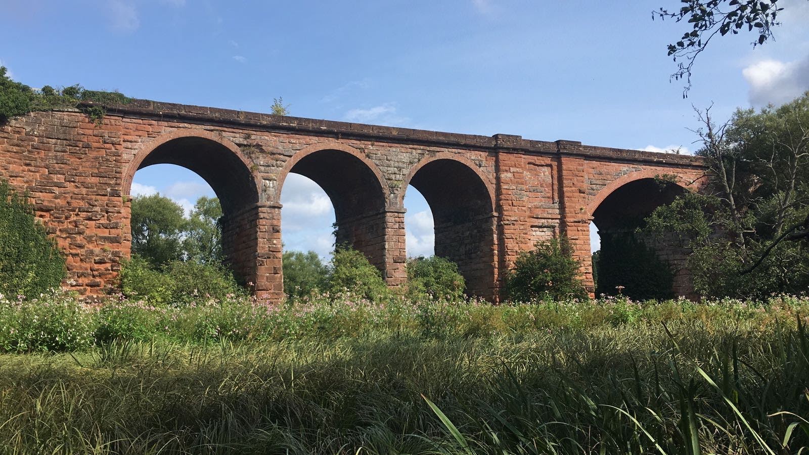 red brick viaduct arches over grassland