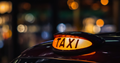 Yellow taxi light up sign on on top of a black hackney carriage 