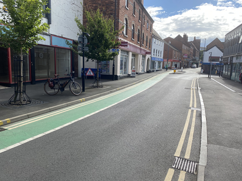 view down road and cycle path with shops either side