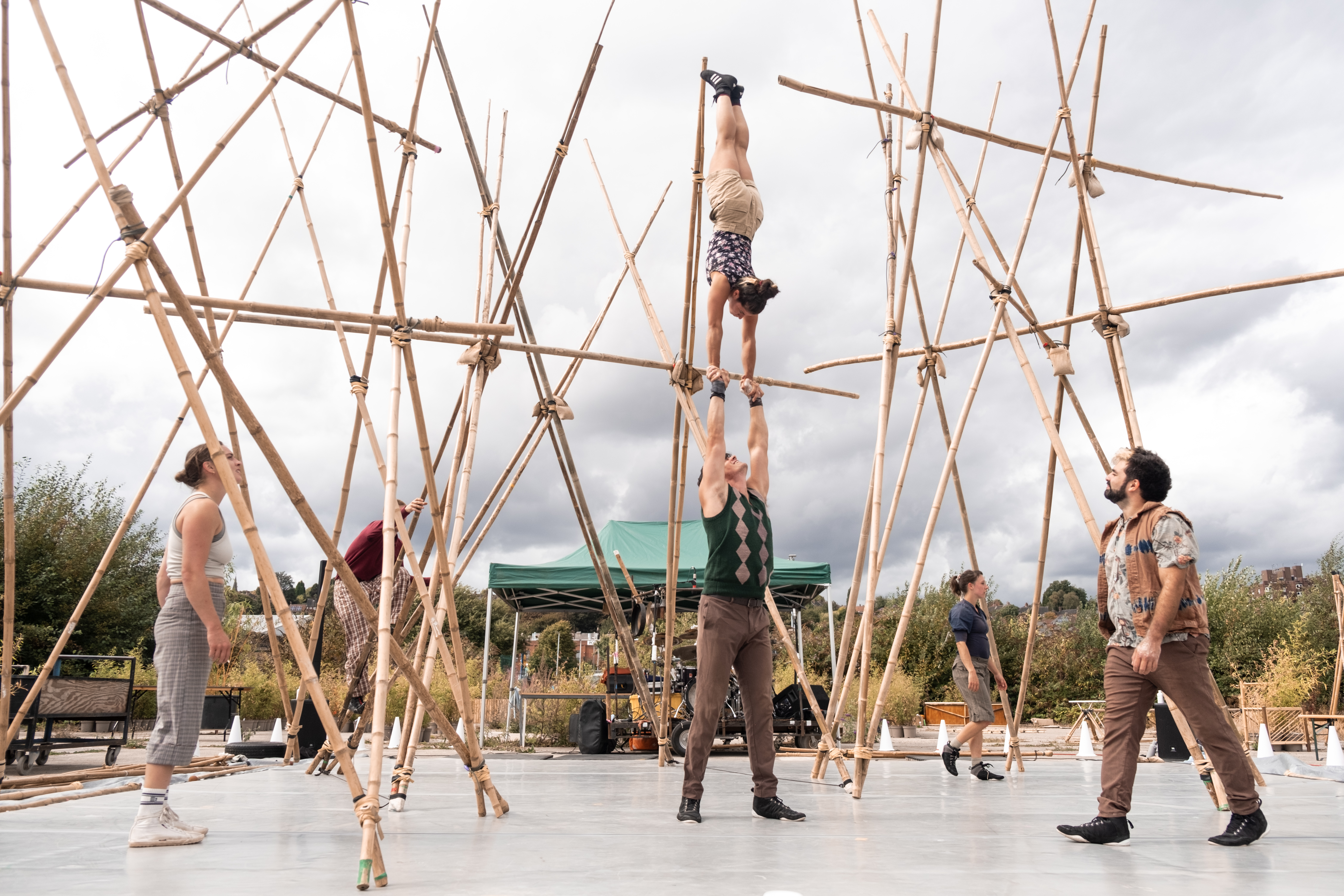  Photo of acrobats performing outdoors on large display of bamboo canes
