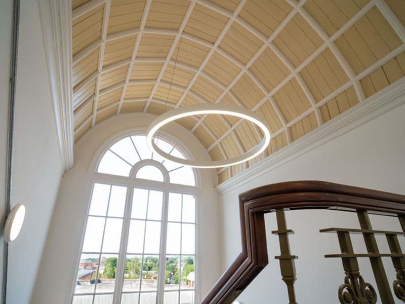 A staircase with a circular light hanging from the ceiling