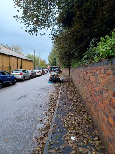 road sweeper cleaning street and footpath from autumn fallen leaves