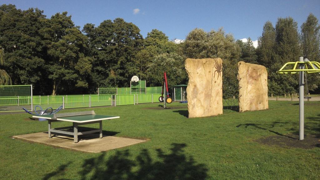 Older children's play area with climbing apparatus located on grassed area in public park.