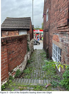 cobbled alley between brick wall and brick building